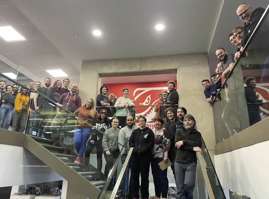 <img src="DambusterStudios_DrivingEDIThroughoutMayAndJune_05.jpg" alt="A photo of the team at Deep Silver Dambuster Studios in their office via the main stairway">